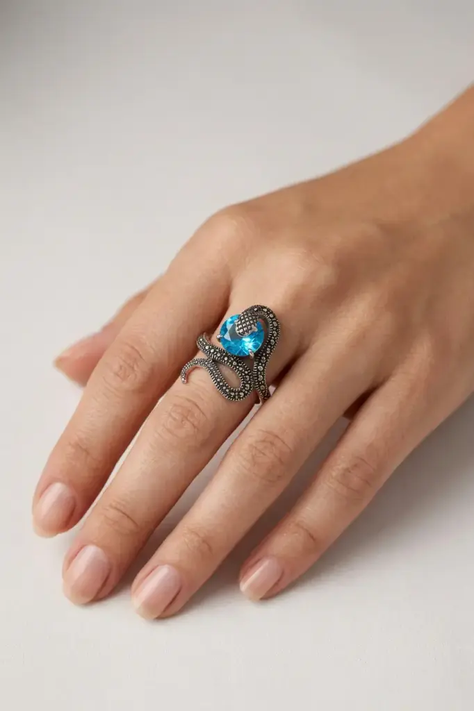 An ornate snake-design ring featuring a round blue stone.