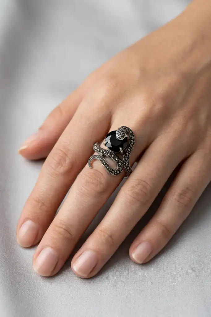 An ornate snake-design ring featuring a round black stone.