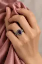 An ornate ring featuring an oval dark-purple stone