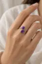 A minimalist open ring featuring two purple stones, one round and one oval.