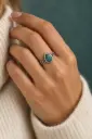 An elegant ring featuring a teal-green pear-shaped stone and a finely patterned band.