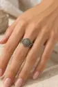 خاتم مزخرف يتوسطه حجر بيضاوي بدرجات الرمادي والبني.