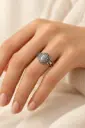 An ornate ring featuring an oval light-gray stone with natural tonal variations.