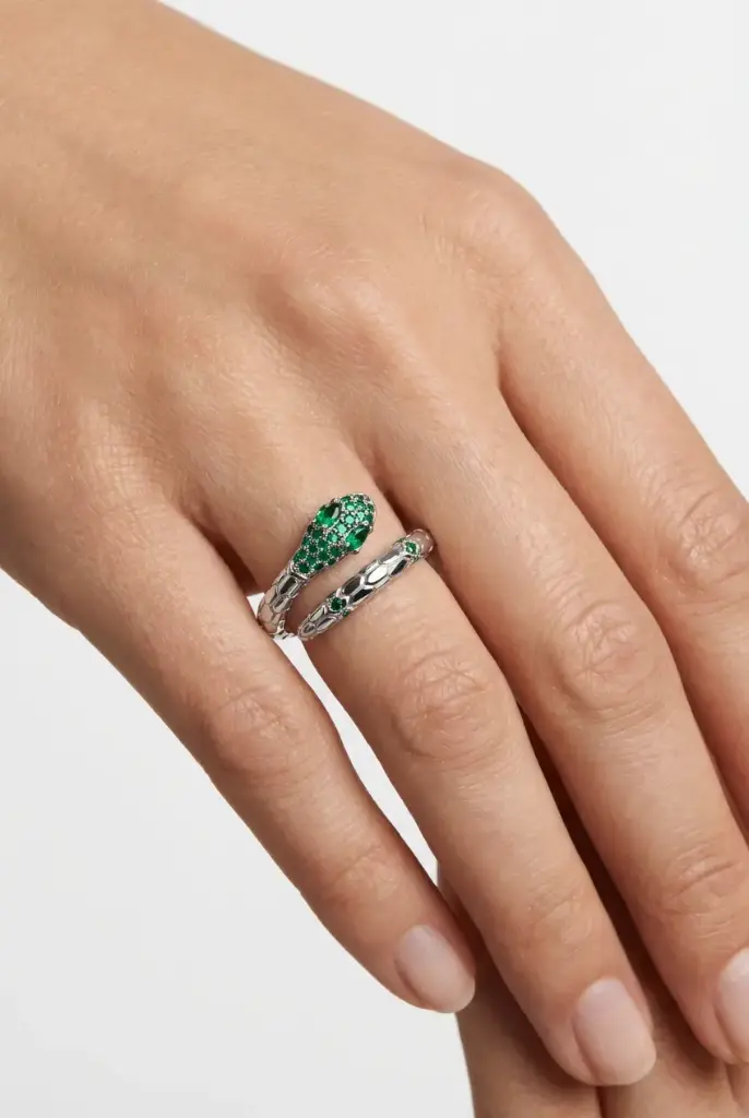 An open snake ring accented with sparkling green stones