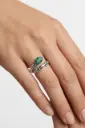 An open snake ring accented with sparkling green stones