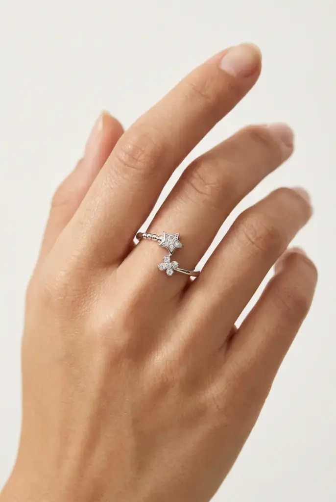 An open silver ring featuring a sparkling star and flower design