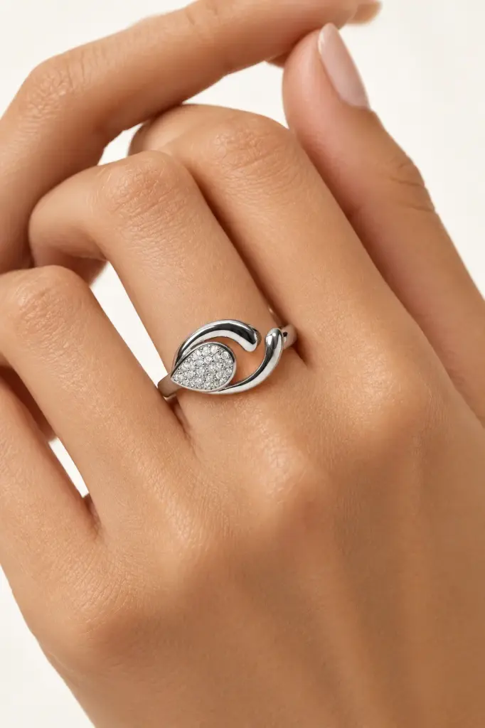 A flowing silver ring featuring an oval cluster of sparkling stones