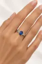 A silver ring with an oval blue stone and clear side stones